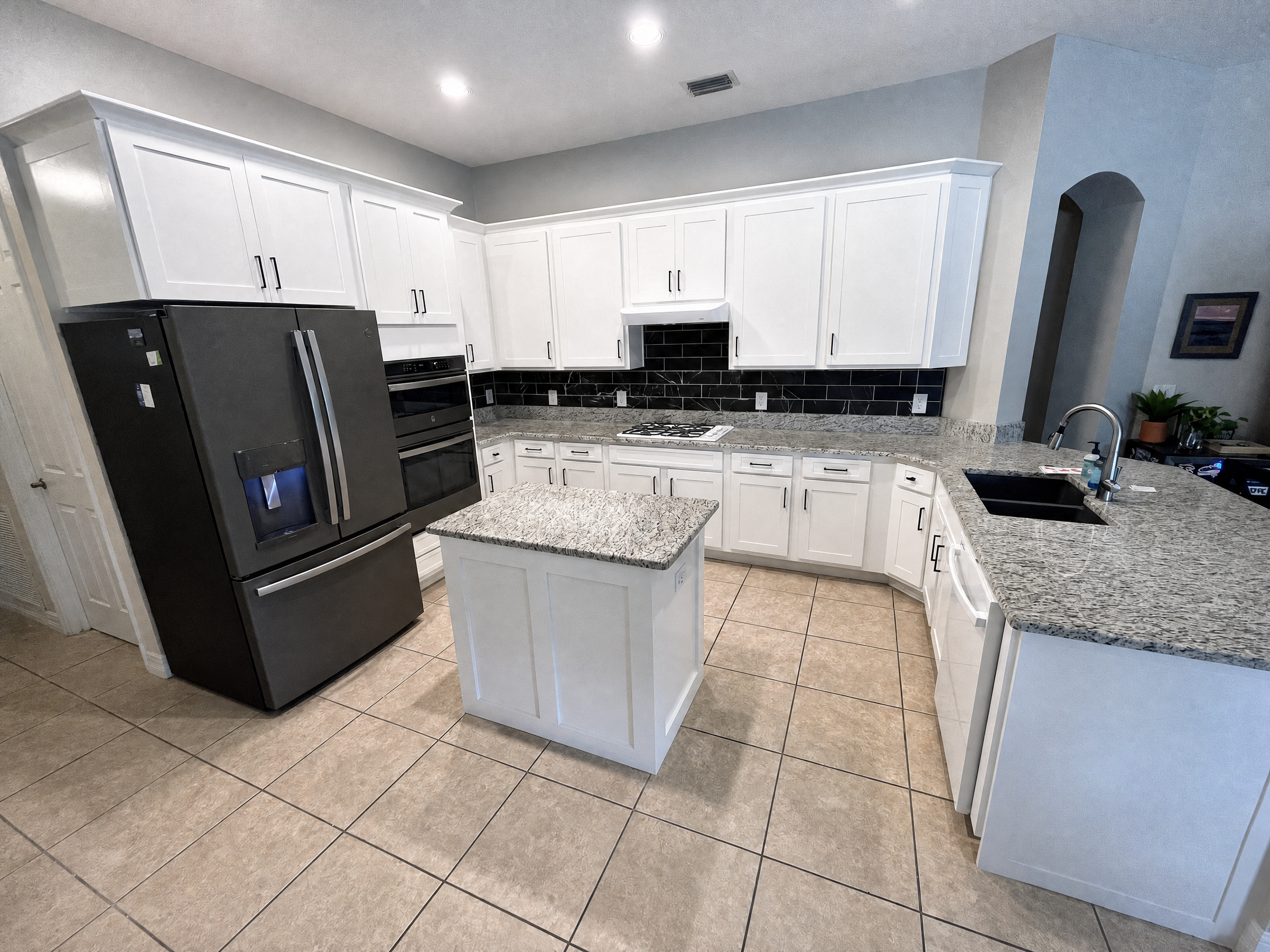 White shaker cabinet refacing with granite island and dark subway backsplash