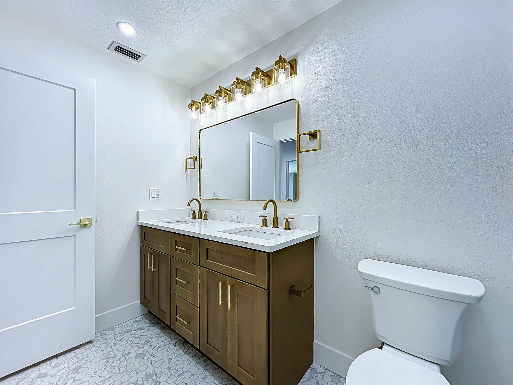 Bathroom remodeling in Tampa Bay — Belleair walnut double vanity with brass sconces